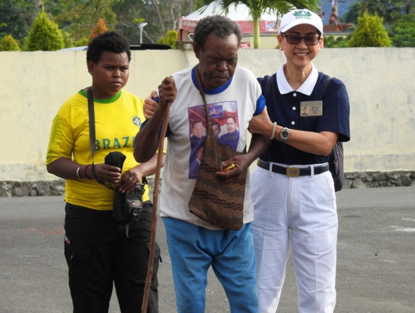 Relawan Tzu Chi Biak, Yenny The, menuntun Ruben (58), salah satu pasien yang akan menjalani pemeriksaan kesehatan.